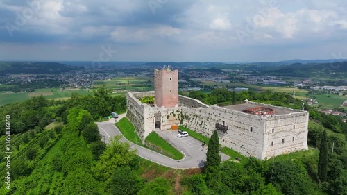 orbiting aerial of the Romeo and Juliet inspirational castle Castello di Giulietta in Vicenza, Italy showcasing the castler perched high on a hill and the surrounding countryside