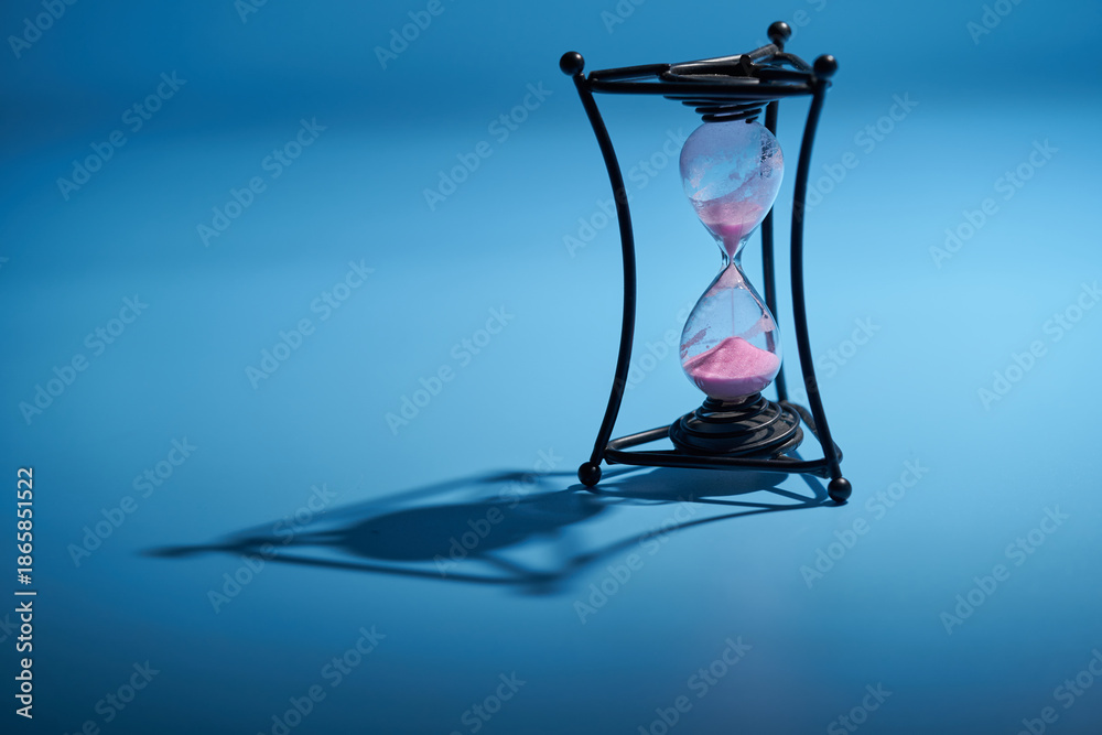 Obraz premium Time concepts hourglass on blue background still life.