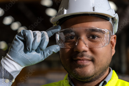 Close up asian man technician engineer wearing and adjust protective safety glasses. Safety equipment for industry factory. Safety at work concept.