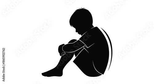 a solitary child sits with knees drawn up head bowed in a pensive and introspective pose silhouette