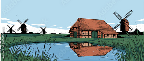 Traditional half-timbered barn with a red tiled roof stands beside a tranquil pond reflecting its facade in a scenic rural landscape with windmills