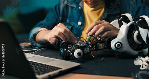 Foto A close-up captures a teenage girl's hands using a soldering iron to connect robot parts