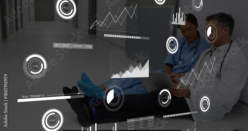 Doctor powering laptop and scrolling panels with nurse pointing at AR charts for medical review
