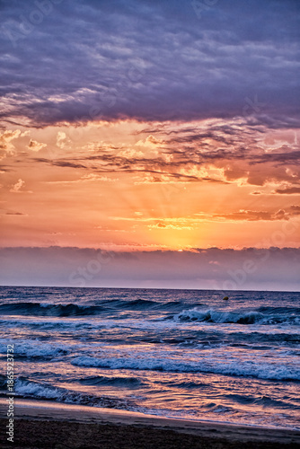 Beautiful sunset over ocean waves with colorful sky during evening hours by the beach