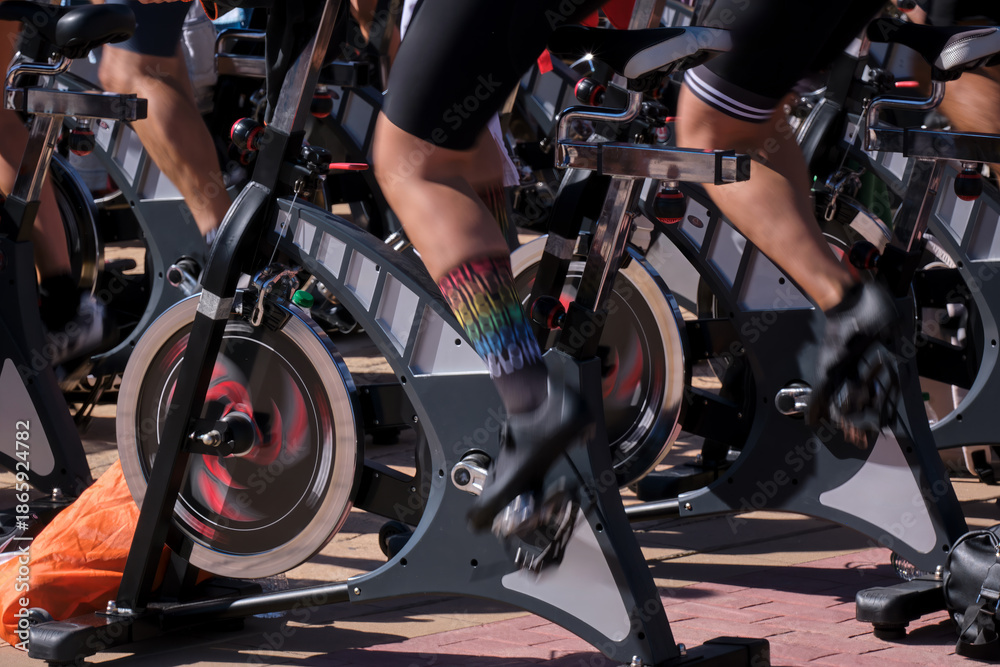 Fototapeta premium Cyclists participating in group spinning class during daytime at fitness event in urban setting