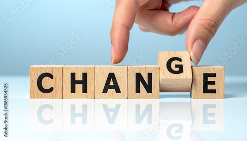 Hand arranging wooden blocks to spell CHANGE from CHANCE.