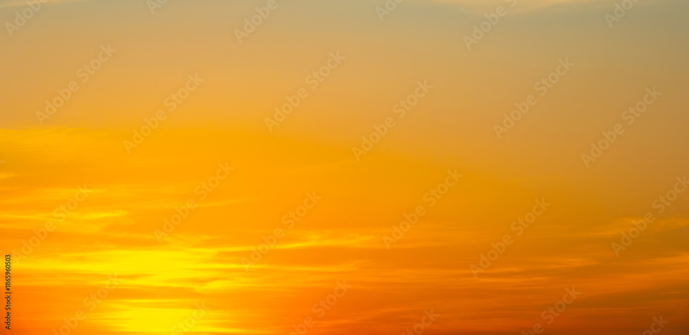 Obraz premium Dramatic golden sunset sky with vivid orange and purple clouds.beautiful twilight sky background with bright orange clouds during sunset.majestic evening sky with colorful cloudscape at golden hour.