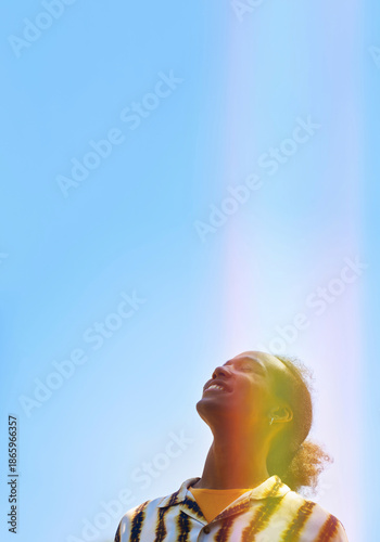 Smiling young man in tie dye shirt looking up outdoors at blue sky