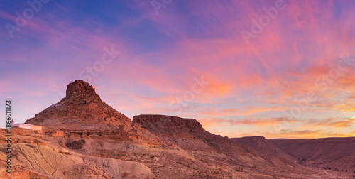 Sunset light over Ksar Guermassa ancient fortified village in Dahar mountains, Tataouine region Tunisia, desert landscape, dramatic sky, cultural heritage, travel
