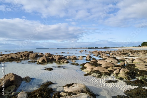 Rocky tidal flats at low tide with rippled sand and clear pools — calm coastal landscape