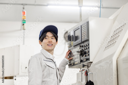 Bild auf Leinwand 工場の操作盤の前で働く男性作業員