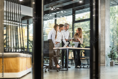Creative business people, planning and meeting and brainstorming, ideas or strategy at office, view from glass wall.
