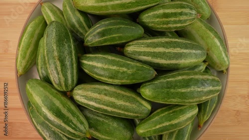 Fresh pointed gourd on plate rotation top view.