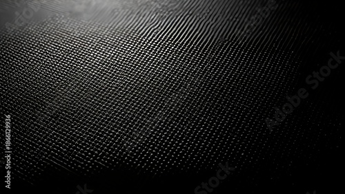 A close up view of a dark textured surface reveals a repeating grid pattern hinting at woven material or a complex design