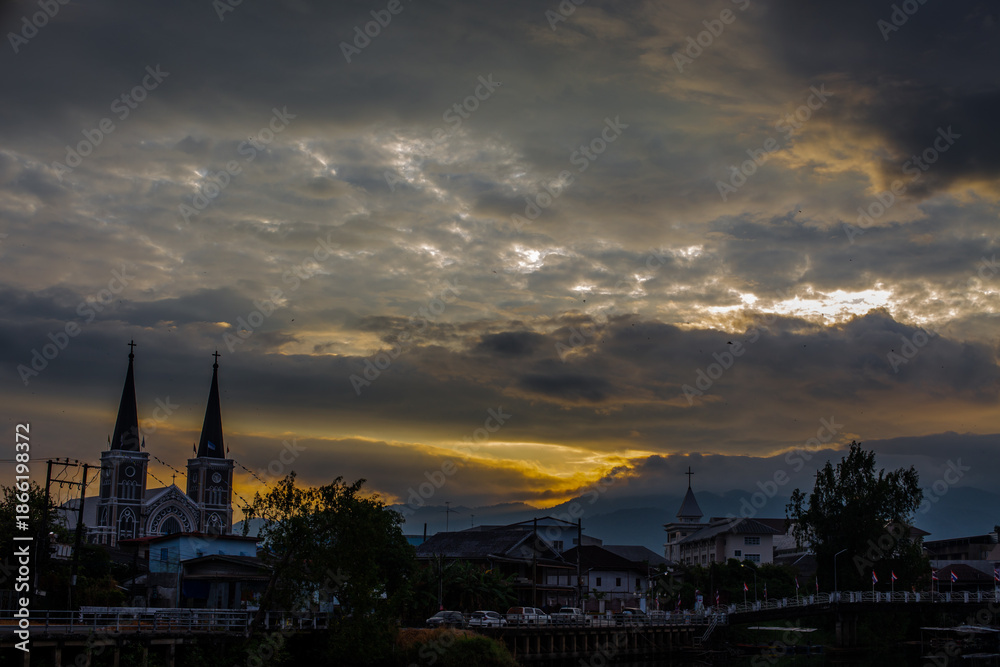 Obraz premium The backdrop of colorful sky lights reflecting off the beautiful river surface at different times of the day, amidst a stunning Christian church in Chanthaburi, Thailand.