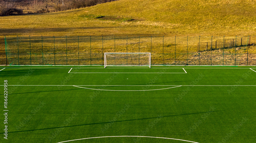 Obraz premium Wide football training field with artificial turf and distant goal, clean open space