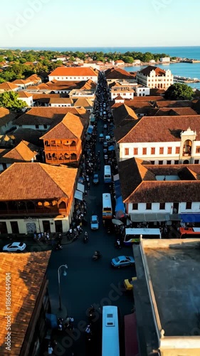 Aerial View of a Historic Town with Traditional Architecture and Busy Streets Surrounded by Greenery and Water Body