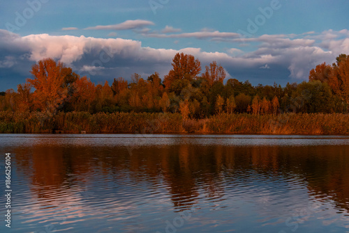 Dramatic storm front over fall shoreline and warm evening light