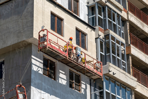 August 21, 2025: Construction lift with workers performing wall finishing on a building site in Novorossiysk, Russia, illustrating modern construction, labor and urban development