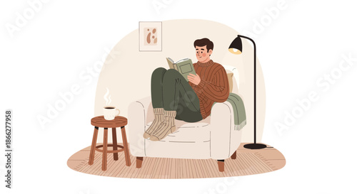 Young man relaxing comfortably in an armchair while reading a book with his cat.