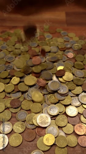Close-up of female hands taking, counting, and dropping a large pile of Euro coins on a wooden floor. Finance and wealth concept