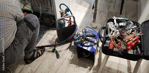 Εκτύπωση καμβά Person repairing refrigerator compressor with gas tanks, refrigeration tools, and copper pipes, professional service technician performing maintenance