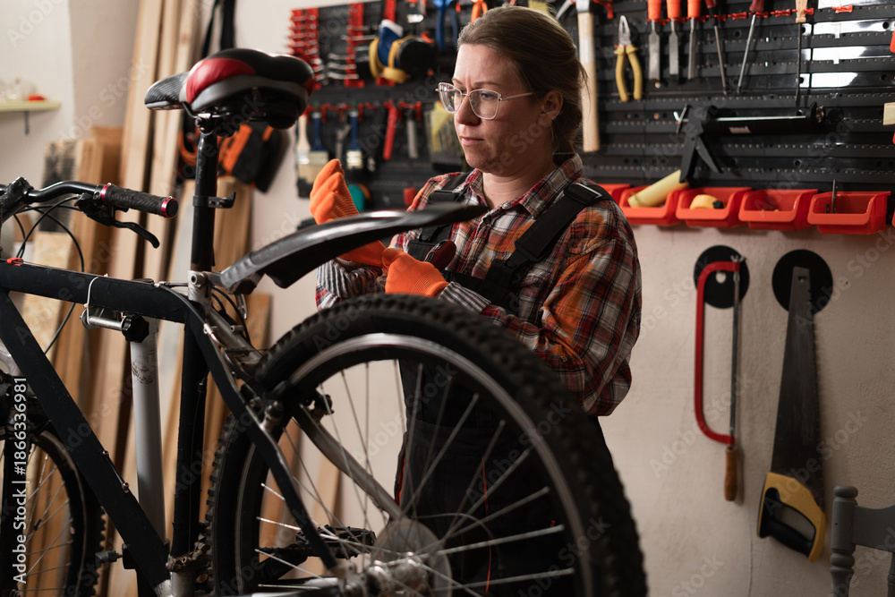 Obraz premium A female mechanic repairs a bicycle in her workshop