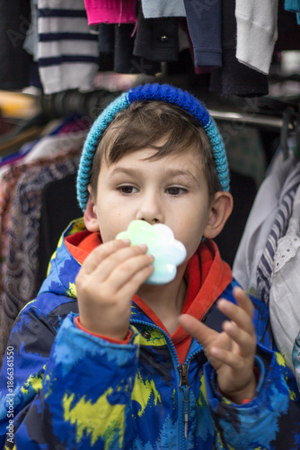 Close-up portrait of a little boy holding a bright paw-shaped fidget toy on his palm.