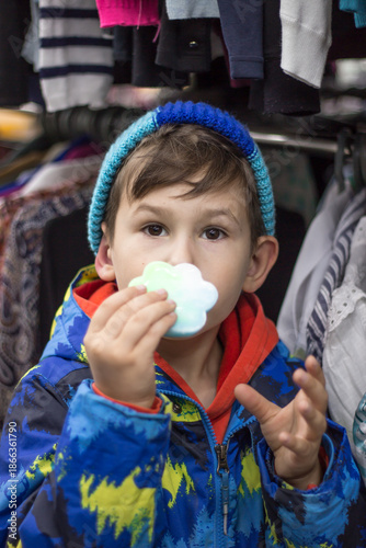 Close-up portrait of a little boy holding a bright paw-shaped fidget toy on his palm.