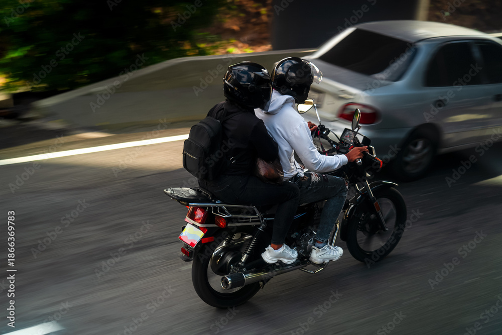 Obraz premium Motorcyclist and passenger driving on highway in downtown Caracas, Latin American traffic, Venezuela.