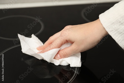 фотографія Woman wiping cooktop with paper towel in kitchen, closeup