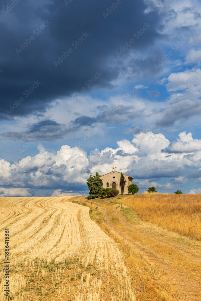 Fototapeta premium Rural chapel standing alone under dramatic sky in Provence, France