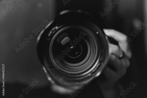 A close-up shot of a professional camera lens with soft reflections and a blurred background. The image highlights photography, optics, and creative equipment.