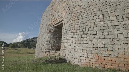 Great Zimbabwe African ruins and monument landmark of ancient civilization in slow motion with historic stone structure and village beneath hill complex at enclosure archaeological site travel spot