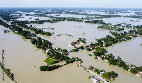 An aerial view shows widespread flooding submerging villages and farmland, with isolated homes and trees standing amid vast floodwaters