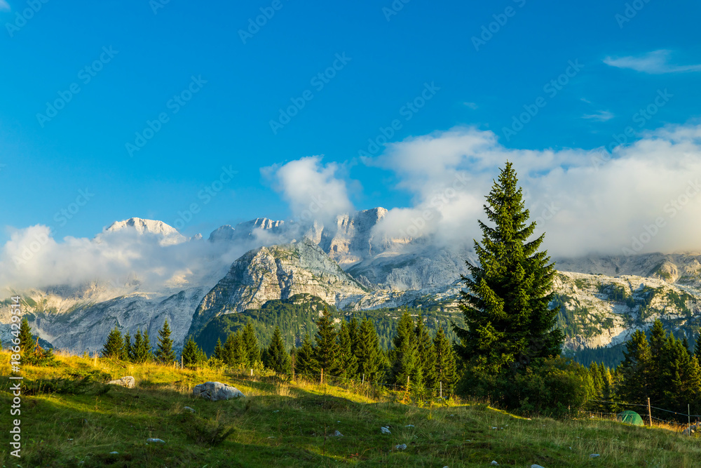 Fototapeta premium Dolomite mountain range landscape with clouds and green grass