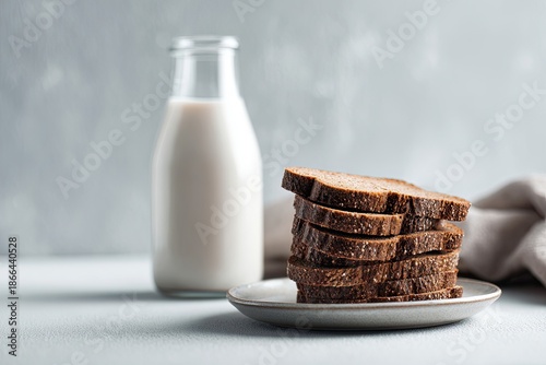 A stack of rye bread slices next to a bottle of white liquid, and a plate
