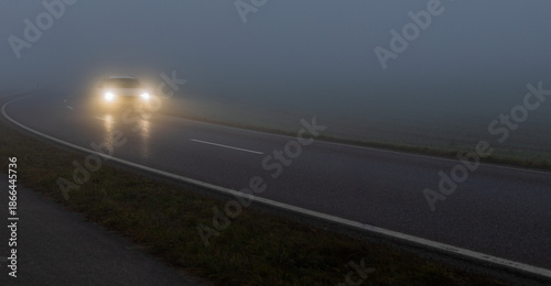 Tableau sur toile Scheinwerfer eines Autos im dichten Nebel auf nasser Landstraße bei Nacht