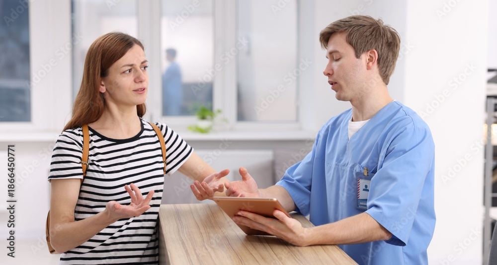 Fototapeta premium Medical assistant helping patient at reception in clinic