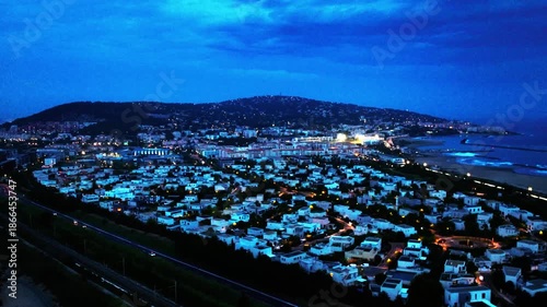 Aerial drone footage of Sète city at night, featuring illuminated urban landscape, harbor lights, and Mediterranean coastal atmosphere in southern France.