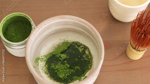 Preparing matcha tea process. Pouring hot water into matcha powder in ceramic bowl