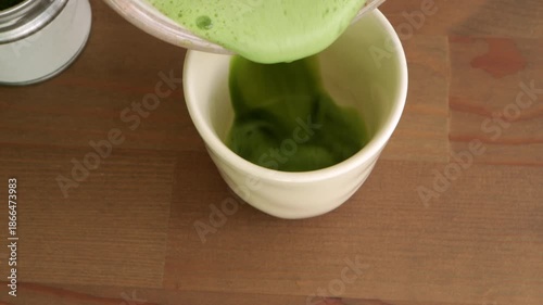 Matcha green tea with foam pouring into ceramic cup