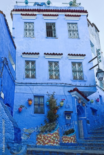 Traditional three-story house in a well-known alley in the medina painted in shades of blue, with colorful planters and pots. Chefchaouen-Morocco-038
