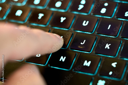Finger pressing key on dark keyboard