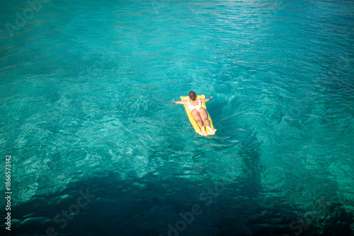 Tableau sur toile Person relaxing on inflatable mattress in clear turquoise sea