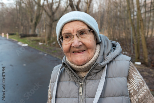 Canvas-taulu Friendly senior woman smiling during a walk on a calm road with bare trees in the background