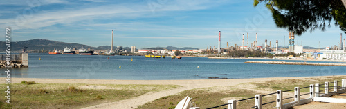 View of the industrial coastline of the Bay of Algeciras, showing an oil refinery and tanker pier in southern Spain. Contrast between natural shoreline and heavy energy infrastructure.