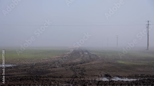 Ground fog flowing over muddy field under fast moving clouds, 4K
