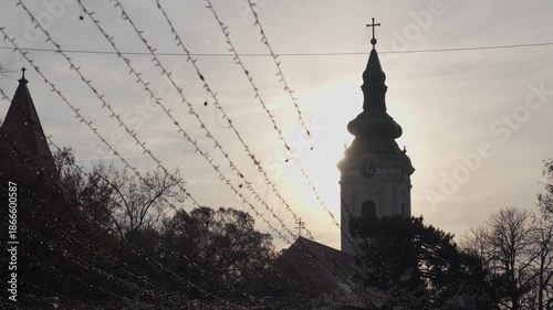Silhouette of Catholic church tower with festive lights at sunset, 4K