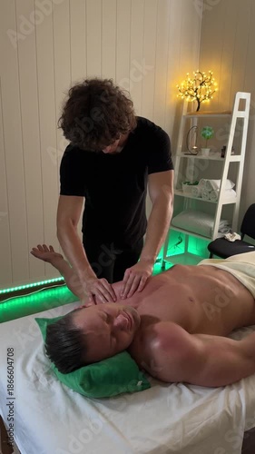 Massage therapist performing chest massage on a male client in a dimly lit spa room